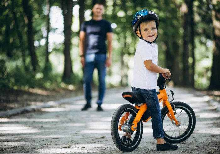 boy on bike father standing background